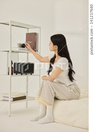Home lifestyle portrait of a woman in a minimal bedroom Home lifestyle portrait of a woman in a minimal bedroom 141237680
