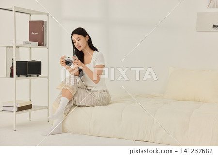 Home lifestyle portrait of a woman in a minimal bedroom Home lifestyle portrait of a woman in a minimal bedroom 141237682