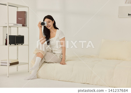 Asian woman arranging decor in a cozy bedroom interior Asian woman arranging decor in a cozy bedroom interior 141237684