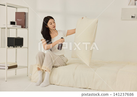 Home lifestyle portrait of a woman in a minimal bedroom Home lifestyle portrait of a woman in a minimal bedroom 141237686