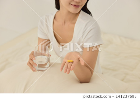 Healthy morning routine with water and vitamins on a bed Healthy morning routine with water and vitamins on a bed 141237693