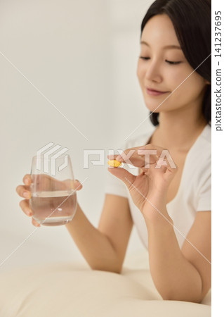 Asian woman sitting in bed with a glass of water Asian woman sitting in bed with a glass of water 141237695