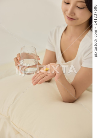 Young Asian woman drinking water on a bed in the morning Young Asian woman drinking water on a bed in the morning 141237696