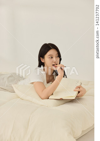 Relaxed home lifestyle with a woman journaling in bed Relaxed home lifestyle with a woman journaling in bed 141237702