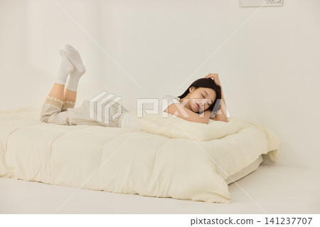 Relaxed woman tying her hair after waking up in a bedroom Relaxed woman tying her hair after waking up in a bedroom 141237707