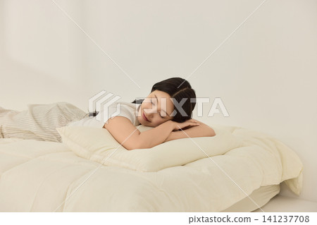 Woman sitting on a cream bed during a calm morning routine Woman sitting on a cream bed during a calm morning routine 141237708