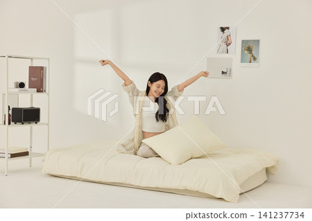 Relaxed home lifestyle portrait in a minimal white bedroom Relaxed home lifestyle portrait in a minimal white bedroom 141237734