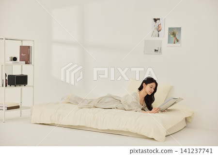 Relaxed home lifestyle portrait in a minimal white bedroom Relaxed home lifestyle portrait in a minimal white bedroom 141237741