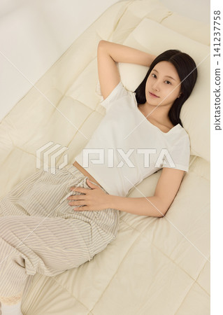 Home lifestyle portrait of a woman resting in bed with a mobile phone Home lifestyle portrait of a woman resting in bed with a mobile phone 141237758