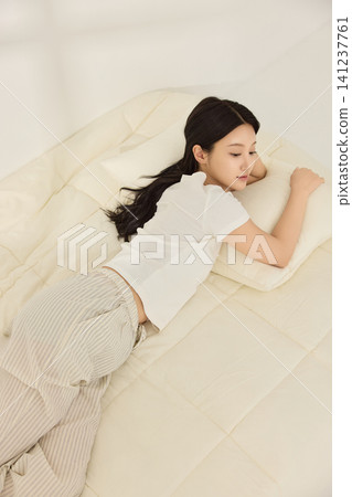 Young Asian woman using a smartphone while lying in bed Young Asian woman using a smartphone while lying in bed 141237761