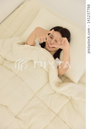 Home lifestyle portrait of a woman resting in bed with a mobile phone Home lifestyle portrait of a woman resting in bed with a mobile phone 141237766