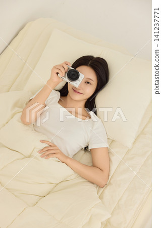Home lifestyle portrait of a woman resting in bed with a mobile phone Home lifestyle portrait of a woman resting in bed with a mobile phone 141237771