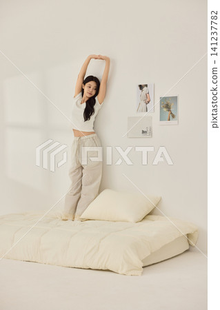 Playful morning lifestyle portrait with a woman on a cream bed 141237782