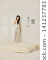 Asian woman posing with a pillow in a white bedroom 141237783