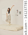 Woman stretching with a pillow in a bright minimal bedroom 141237785