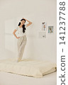 Young Asian woman standing on a bed and holding a large pillow 141237788