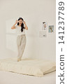 Woman stretching with a pillow in a bright minimal bedroom 141237789