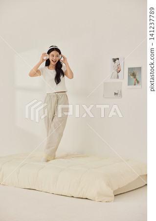 Woman stretching with a pillow in a bright minimal bedroom 141237789