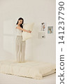 Asian woman posing with a pillow in a white bedroom 141237790