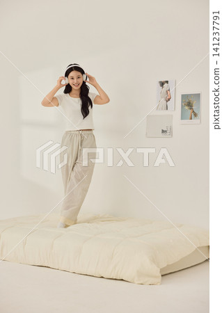 Playful morning lifestyle portrait with a woman on a cream bed 141237791