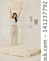 Young Asian woman standing on a bed and holding a large pillow 141237792