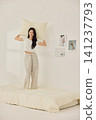 Woman stretching with a pillow in a bright minimal bedroom 141237793