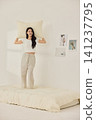 Playful morning lifestyle portrait with a woman on a cream bed 141237795