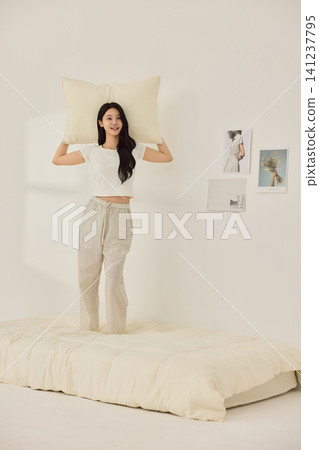 Playful morning lifestyle portrait with a woman on a cream bed Playful morning lifestyle portrait with a woman on a cream bed 141237795