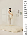 Woman stretching with a pillow in a bright minimal bedroom 141237796