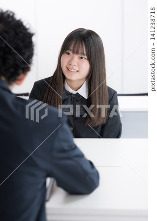 A Japanese high school girl having a career consultation with a teacher in a classroom; an image of a cram school or school where students discuss their future with smiles during individual consultations. A Japanese high school girl having a career consultation with a teacher in a classroom; an image of a cram school or school where students discuss their future with smiles during individual consultations. 141238718