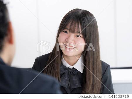 A Japanese high school girl having a career consultation with a teacher in a classroom; an image of a cram school or school where students discuss their future with smiles during individual consultations. 141238719