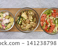 Top-Down View of Three Different Salads in Glass Bowls on a Wooden Board 141238798