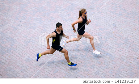 Top view of urban running couple on paved city square. Top view of urban running couple on paved city square. 141239127