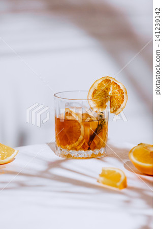 Orange cocktail with dried citrus garnish, rosemary and soft summer shadows. Orange cocktail with dried citrus garnish, rosemary and soft summer shadows. 141239142