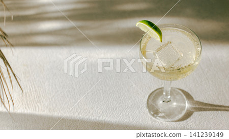 Elegant coupe cocktail with lime garnish, ice and wide clean copy space. Elegant coupe cocktail with lime garnish, ice and wide clean copy space. 141239149