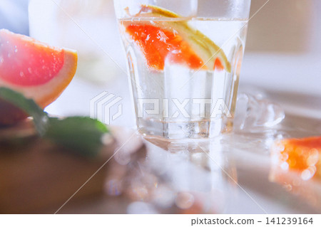 Sparkling grapefruit water close-up with glass, ice and blurred citrus foreground Sparkling grapefruit water close-up with glass, ice and blurred citrus foreground 141239164