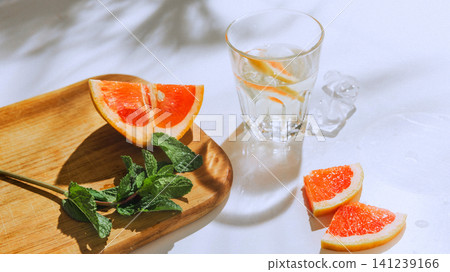 Citrus mocktail still life with grapefruit, mint and copy space in hard sunlight. Citrus mocktail still life with grapefruit, mint and copy space in hard sunlight. 141239166