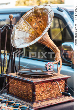 Vintage gramophone with an ornate brass horn and intricate wooden base on a market table. Horizontal Vintage gramophone with an ornate brass horn and intricate wooden base on a market table. Horizontal 141239229