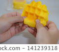 A child's hands playing with a sweets-shaped squishy toy. 141239318