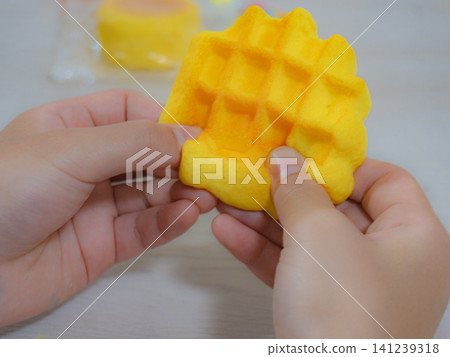 孩子的小手正在玩弄一個糖果形狀的軟綿綿玩具。 孩子的小手正在玩弄一個糖果形狀的軟綿綿玩具。 141239318