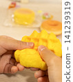 A child's hands playing with a sweets-shaped squishy toy. 141239319