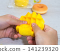 A child's hands playing with a sweets-shaped squishy toy. 141239320