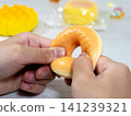A child's hands playing with a sweets-shaped squishy toy. 141239321