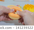 A child's hands playing with a sweets-shaped squishy toy. 141239322