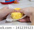 A child's hands playing with a sweets-shaped squishy toy. 141239323