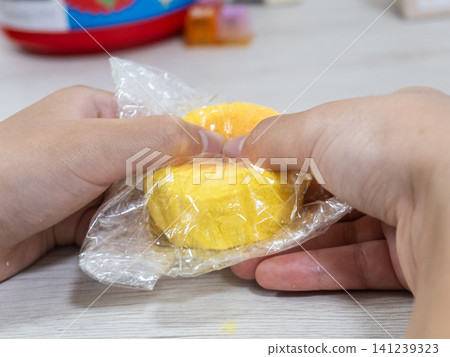 孩子的小手正在玩弄一個糖果形狀的軟綿綿玩具。 孩子的小手正在玩弄一個糖果形狀的軟綿綿玩具。 141239323