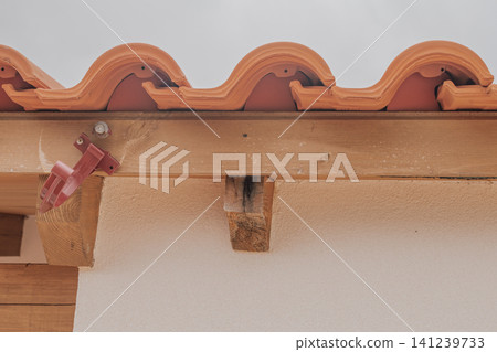 Horizontal close up of a broken home roof drainage system with only one damaged plastic gutter bracket left on a wooden beam showing poor installation and decay Horizontal close up of a broken home roof drainage system with only one damaged plastic gutter bracket left on a wooden beam showing poor installation and decay 141239733