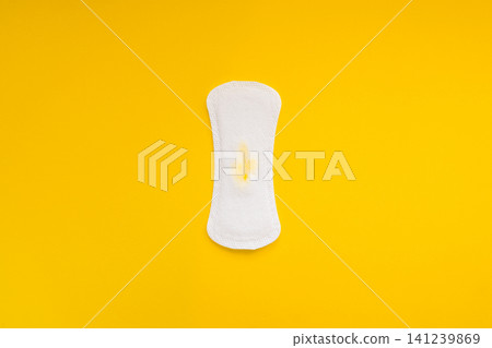 Sanitary Pad with Small Yellow Stain on Yellow Background Sanitary Pad with Small Yellow Stain on Yellow Background 141239869