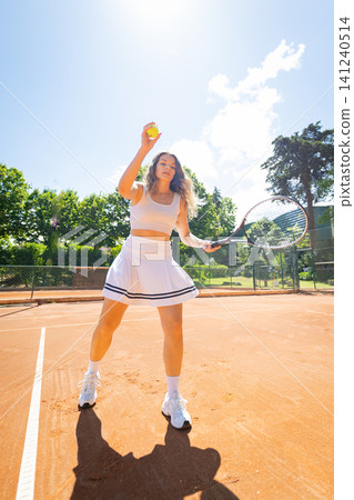 Tennis player prepares to serve a yellow ball on a clay court during sunny weather Tennis player prepares to serve a yellow ball on a clay court during sunny weather 141240514