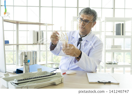 Orthopedic doctor in his office. Orthopedic doctor explain the ankle bone structure  to the patient. 141240747